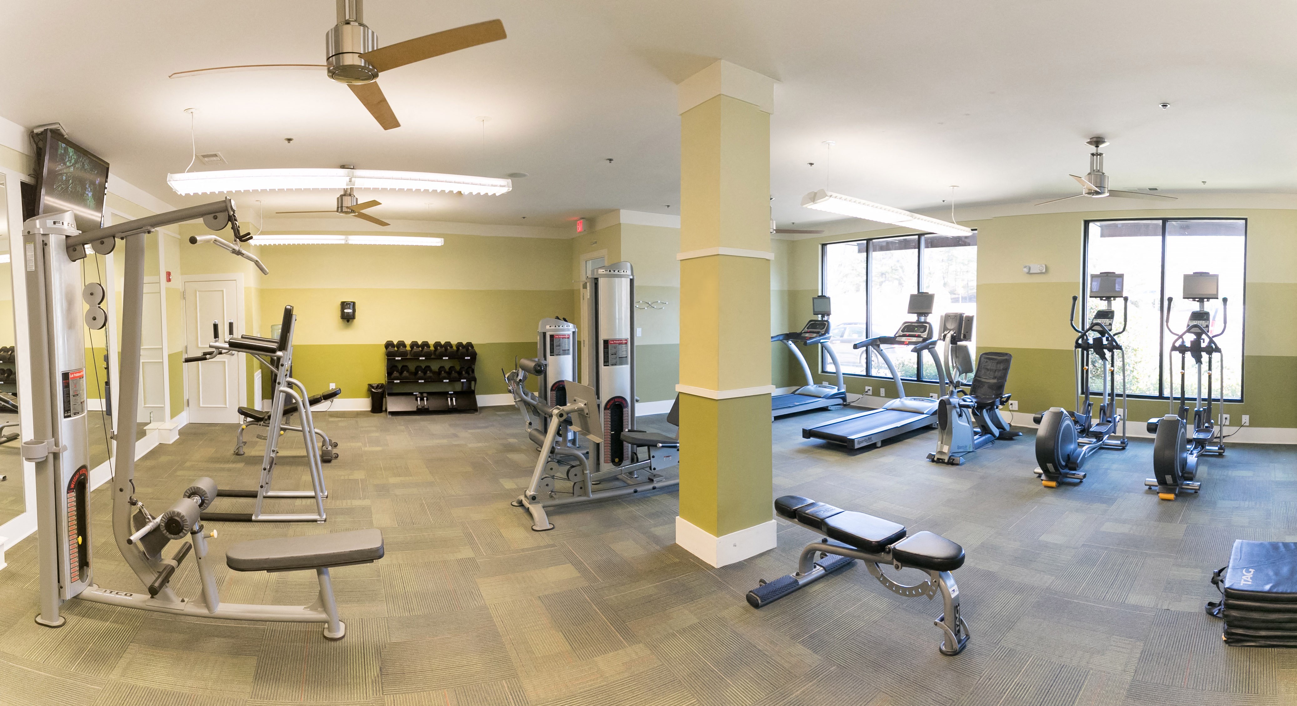 Indoor spacious fitness center with multiple workout equipment.